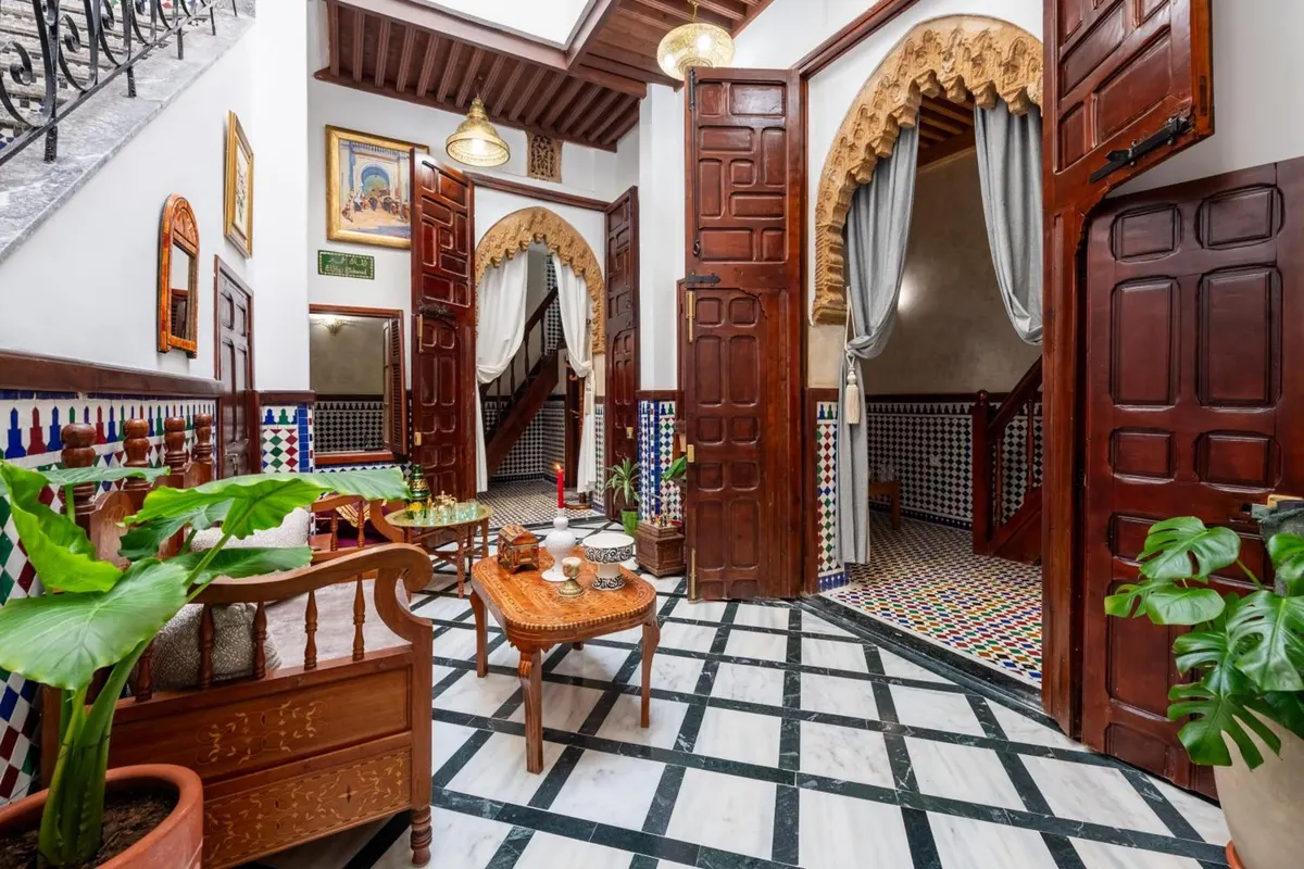 The patio lounge: carved dark-wood doors, horseshoe arch, black-and-white marble floor