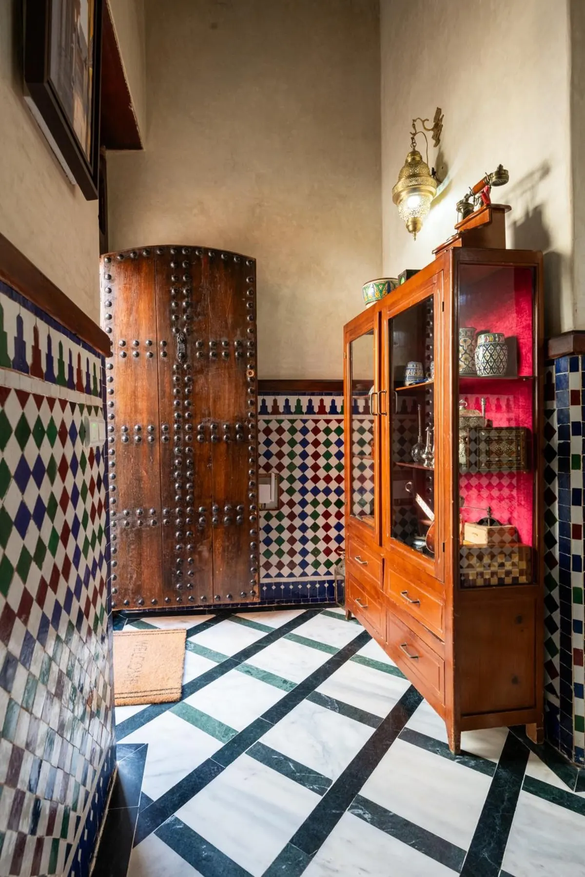 Black-and-white marble floor laid on the diagonal beside a carved cabinet