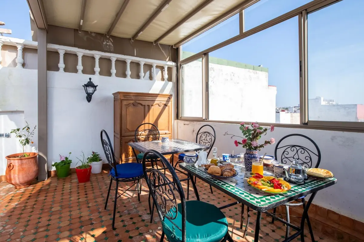 Breakfast on the roof terrace: croissants, fruit platter, orange juice and a silver teapot on a green zellige table