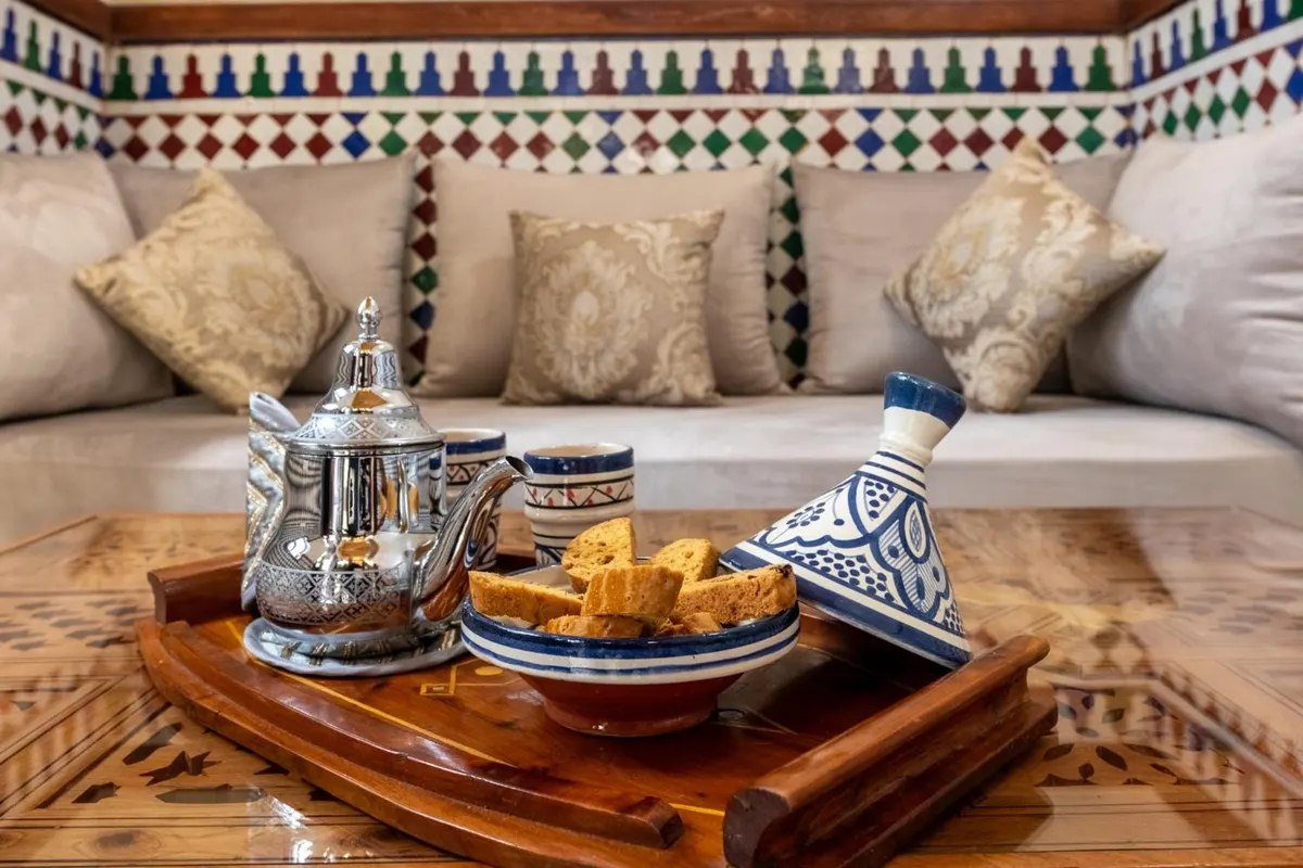 Welcome tray: silver teapot, Moroccan cookies and a painted tagine pot on the banquette