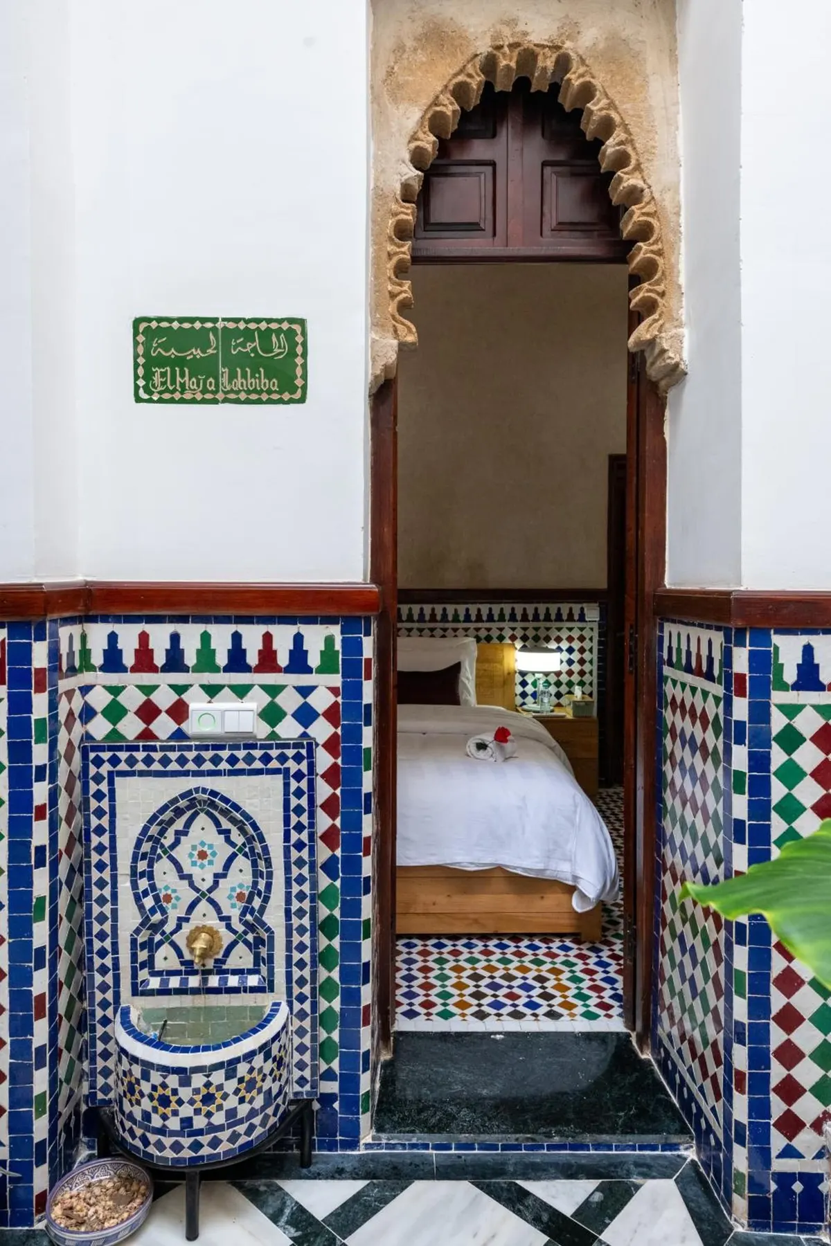 The single room seen through a carved arch from the patio, with its green name plaque